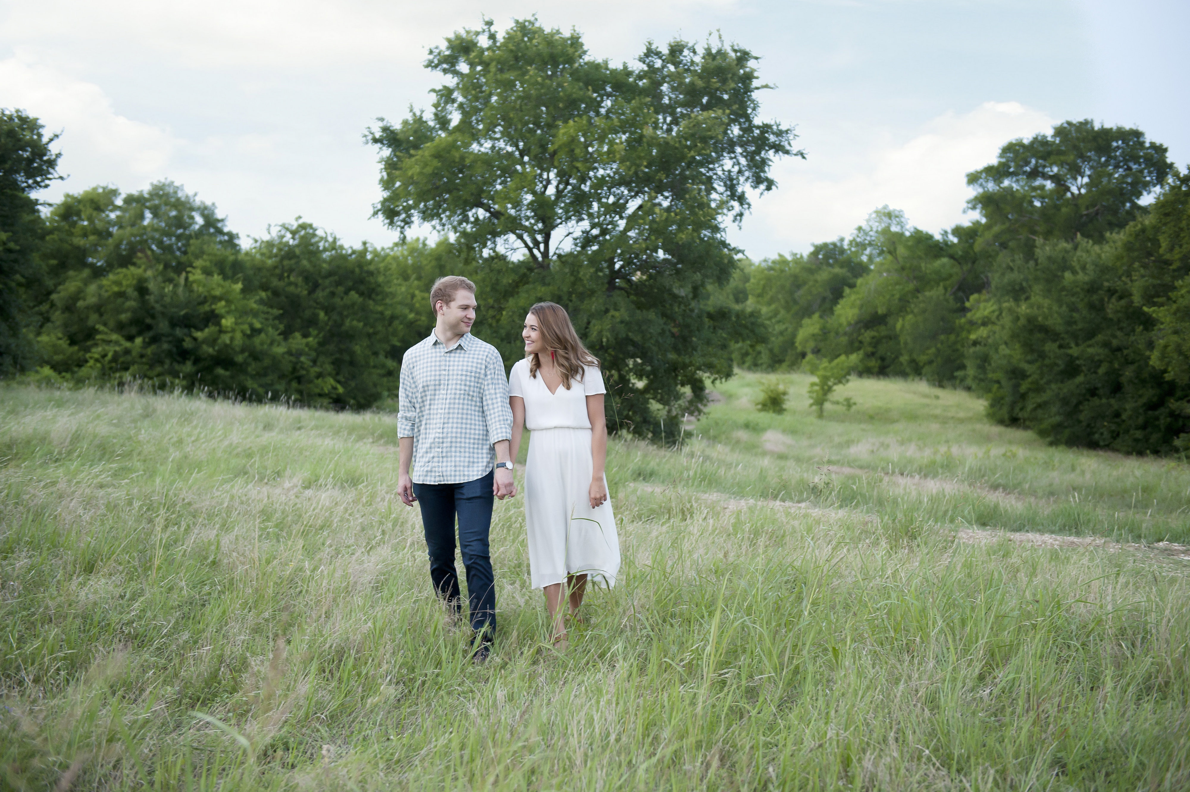 Couple Strolling Holding Hands in a Grassy Field